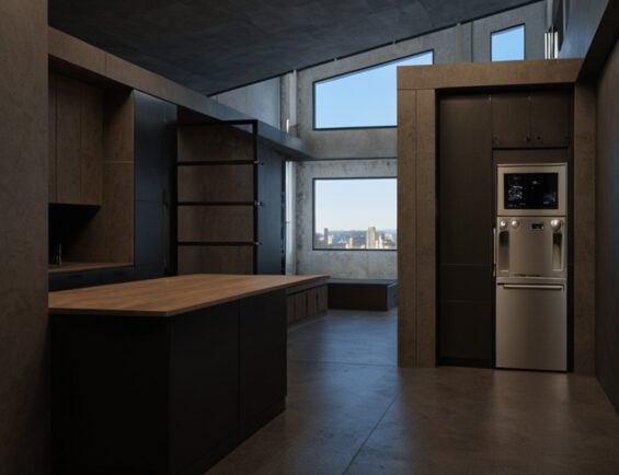 modern kitchen features dark cabinetry, a wooden island, and large windows with a city view.